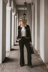 a lady in a white shirt, a black knit jacket and a pair of black pants
